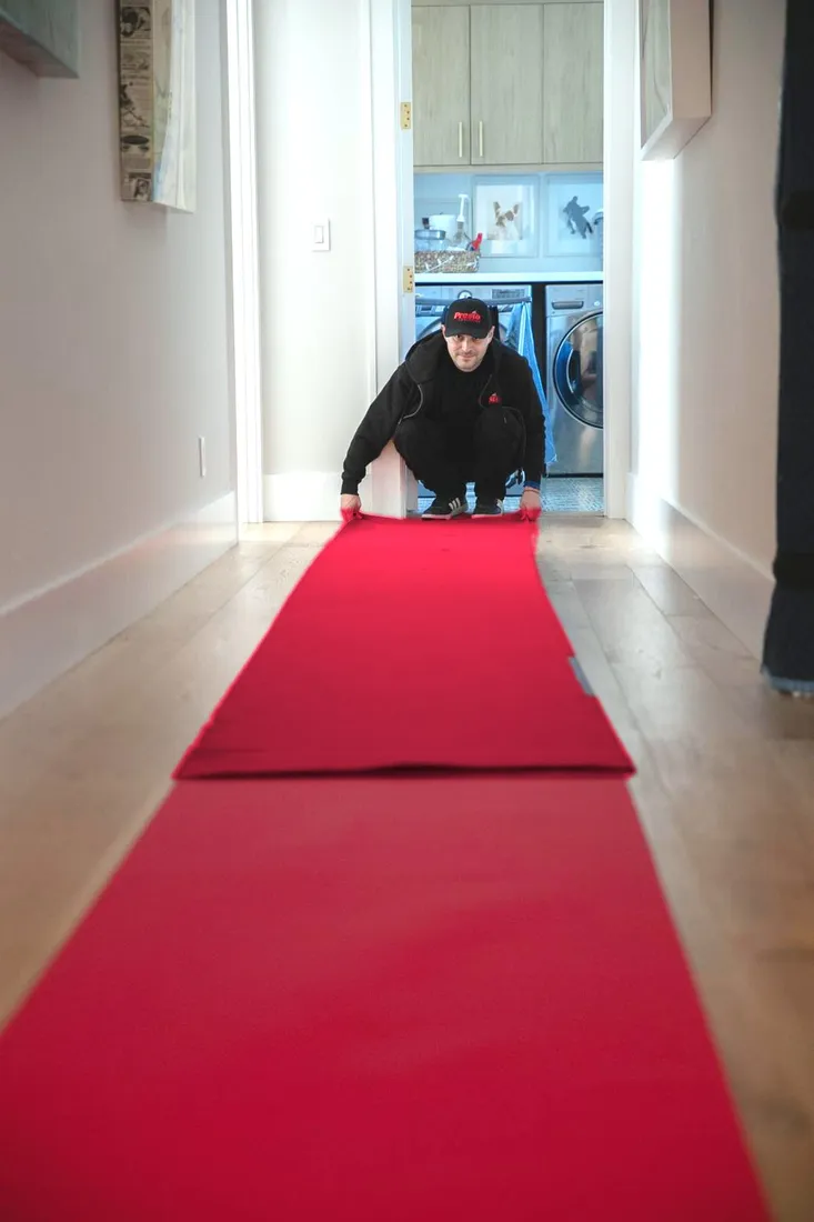 Presto mover rolling out a red floor-protection runner down a hallway